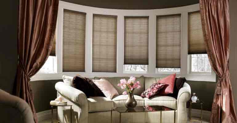 Brown honeycomb shades in living room bow window.